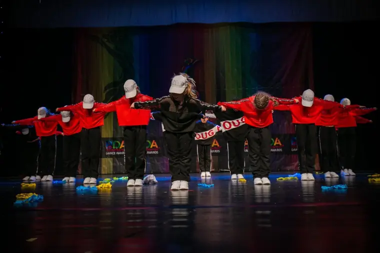 Coregrafie de grup pe scenă, în roșu și negru